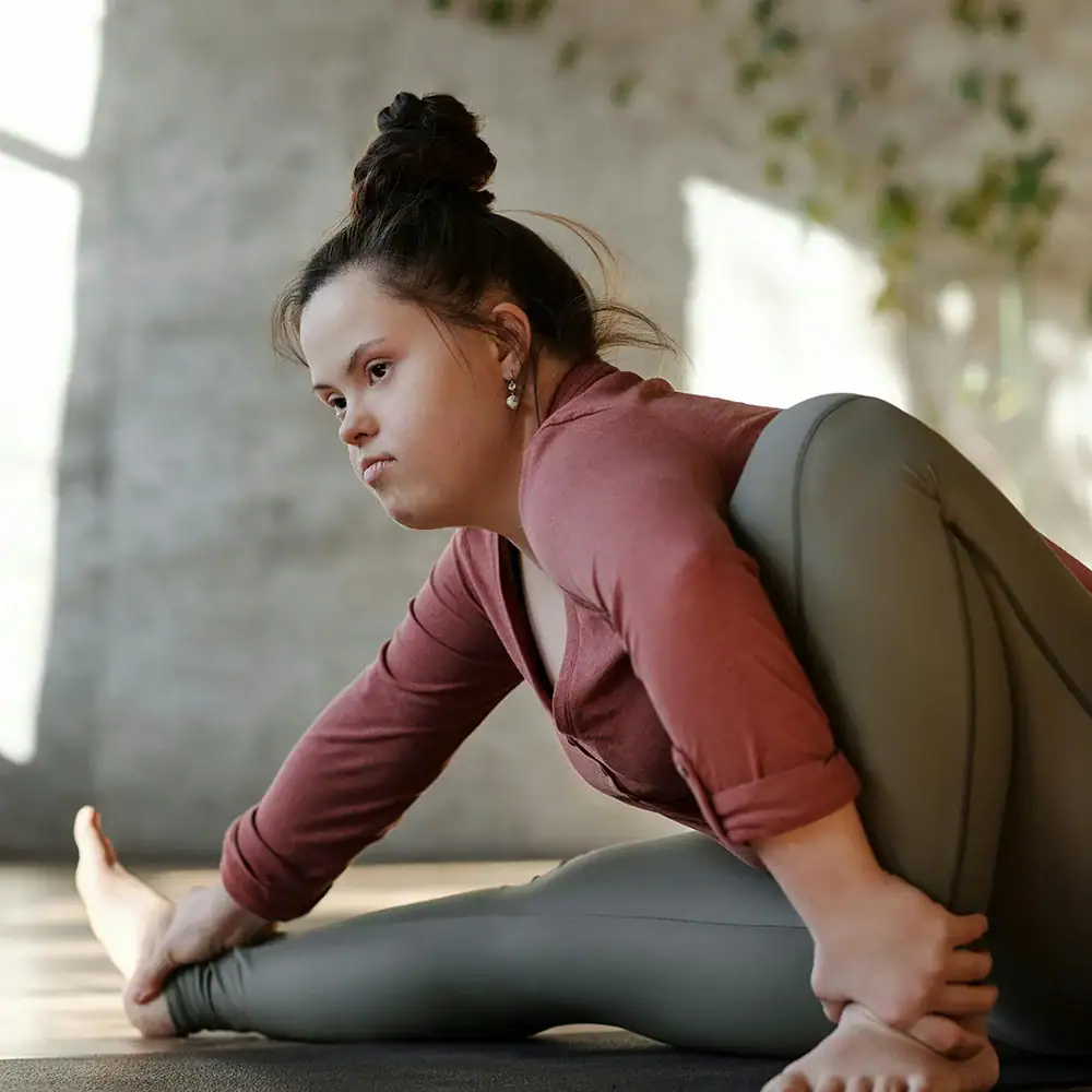 Woman practicing adaptive yoga for disability support and rehabilitation.